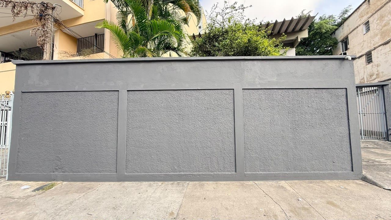 Vista da rua: testada do lote na Av. Geremário Dantas, com prédio vizinho já erguido à esquerda